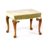 A QUEEN ANNE WALNUT STOOL with upholstered top standing on shaped cabriole legs with pad feet and