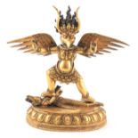 A 19TH CENTURY TIBETAN GILT BRONZE SCULPTURE depicting Garuda triumphing over nagaTibet, 20cm high.