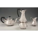A GEORGE V ART NOUVEAU SILVER FOUR-PIECE TEA SERVICE of faceted baluster form with hinged lids