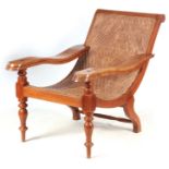 A 19TH CENTURY INDIAN HARDWOOD PLANTATION CHAIR with palm woven seat and hinged foot rests