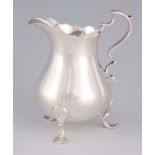 AN ELIZABETH II SILVER CREAM JUG with shaped handle, standing on three legs, by Roberts and Belk,