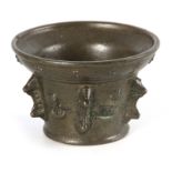 A 17TH CENTURY FRENCH BRONZE MORTAR of tapering form cast with portrait heads and flowerheads 13cm