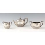 A LATE VICTORIAN SILVER THREE PIECE TEA SERVICE each having half reeded shaped bodies and angled