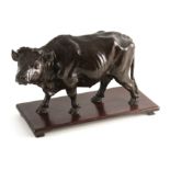 A MEIJI PERIOD JAPANESE PATINATED BRONZE SCULPTURE ON HARDWOOD STAND modelled as a walking bull