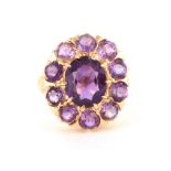 A LADIES 9CT YELLOW GOLD AMETHYST CLUSTER RING the brilliant-cut centre stone surrounded by 10