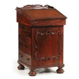 A WILLIAM IV ROSEWOOD DAVENPORT with angled hinged pull forward top fitted with a bank of side