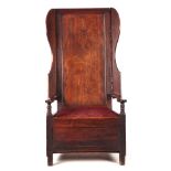 A GOOD 18TH CENTURY WALNUT AND ELM LAMBING CHAIR with raised panelled back flanked by shaped