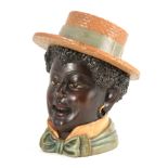 A CARVED WOOD AND PAINTED TOBACCO JAR formed as a coloured boy wearing a straw hat 28cm high.