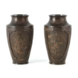 A PAIR OF JAPANESE BRONZE WHITE METAL PANELLED VASES with figural and landscape scenes surrounded by