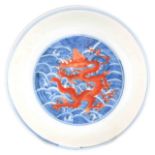 A 19TH CENTURY CHINESE DISH decorated with blue waves and five claw dragons - marked to the