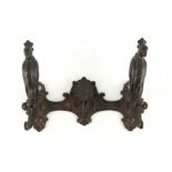 A BRONZE METAL COAT RACK BY PAUL KOCH with central mask hook flanked by hinged parrots, their