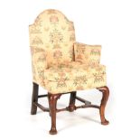 AN EARLY 18TH CENTURY WALNUT UPHOLSTERED ARMCHAIR with arched back, scrolled arms and loose