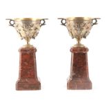 A PAIR OF 19TH CENTURY FRENCH TWO HANDLED SILVERED BRONZE AND MARBLE PEDASTEL URNS cast in high