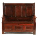 AN EARLY 18TH CENTURY OAK BOX SETTLE with three fielded panels to the back above open arms with lift