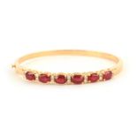 AN 18CT YELLOW GOLD RUBY AND DIAMOND HINGED BANGLE having six brilliant-cut rubies, app. 4.5ct,