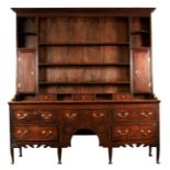 AN 18TH CENTURY SHROPSHIRE OAK DRESSER AND RACK with unusual shaped base having an arched kneehole