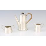 A 1920'S SILVER THREE PIECE TEA SET of tapered form, the teapot having a hinged lid and whicker