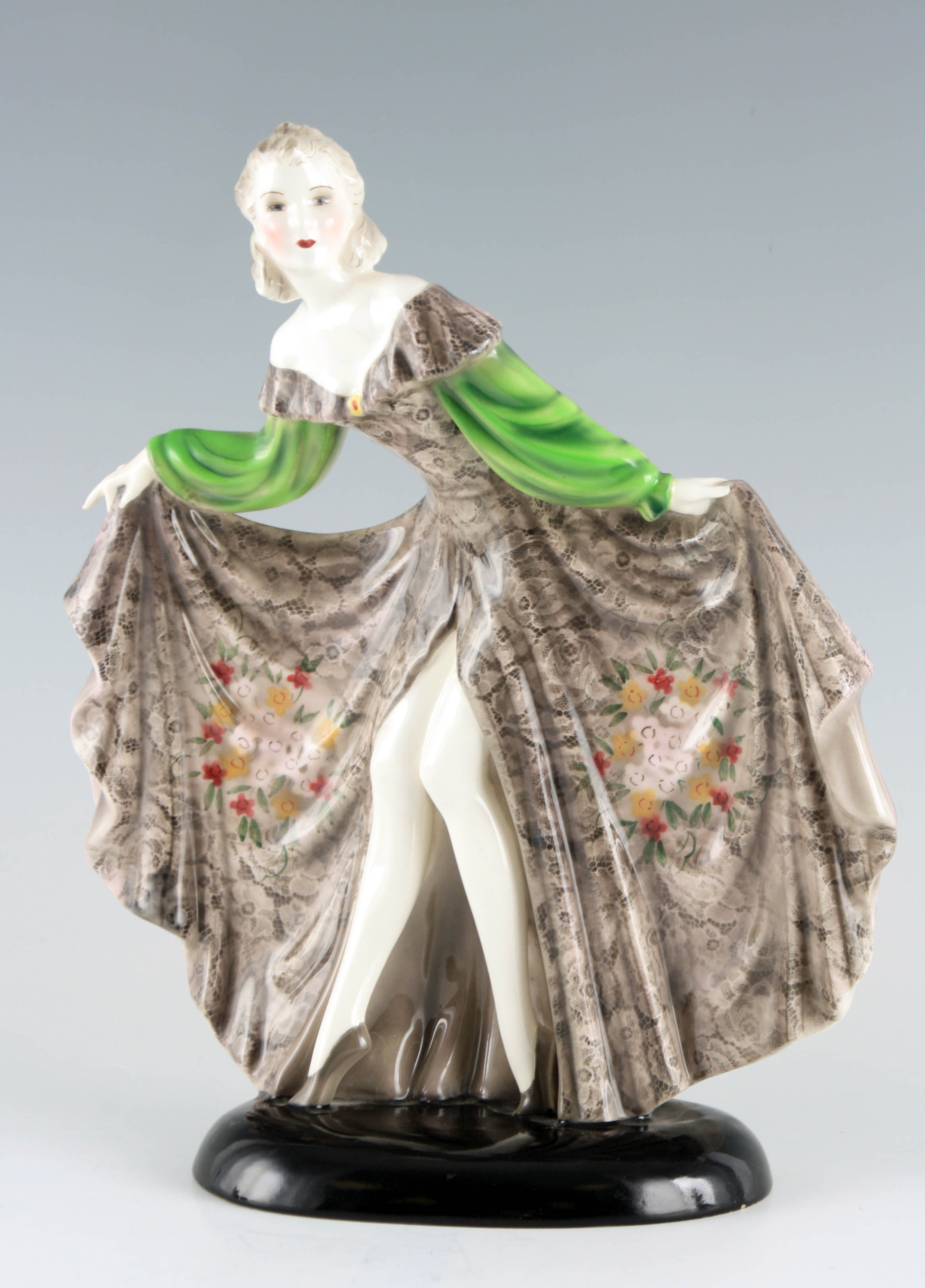 A STYLISH GOLDSCHEIDER STANDING FIGURE OF A YOUNG LADY in an elaborate swept dress 32cm high 27cm