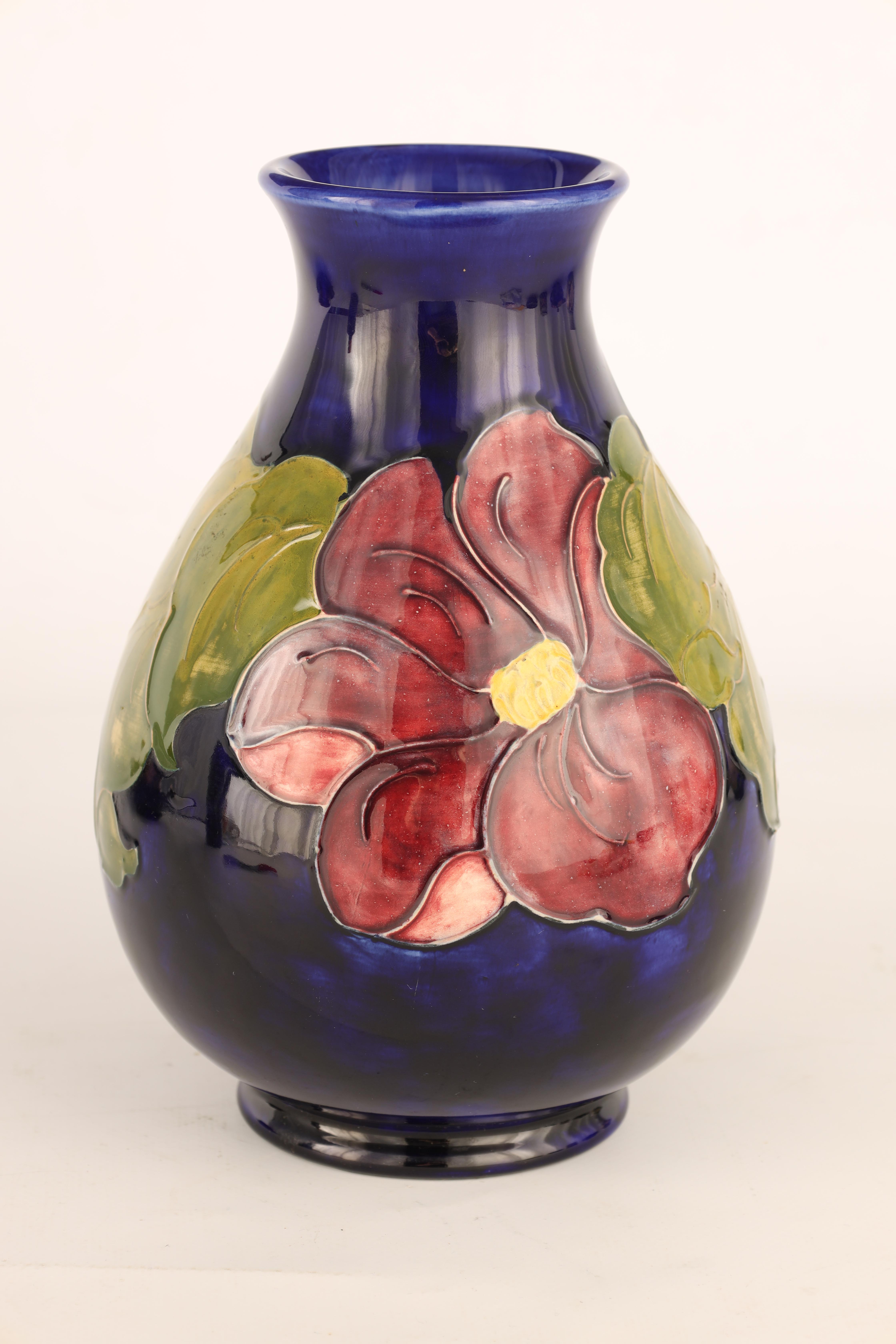 A WALTER MOORCROFT FOOTED OVOID VASE decorated in the Clematis pattern on a dark blue mottled - Image 3 of 4