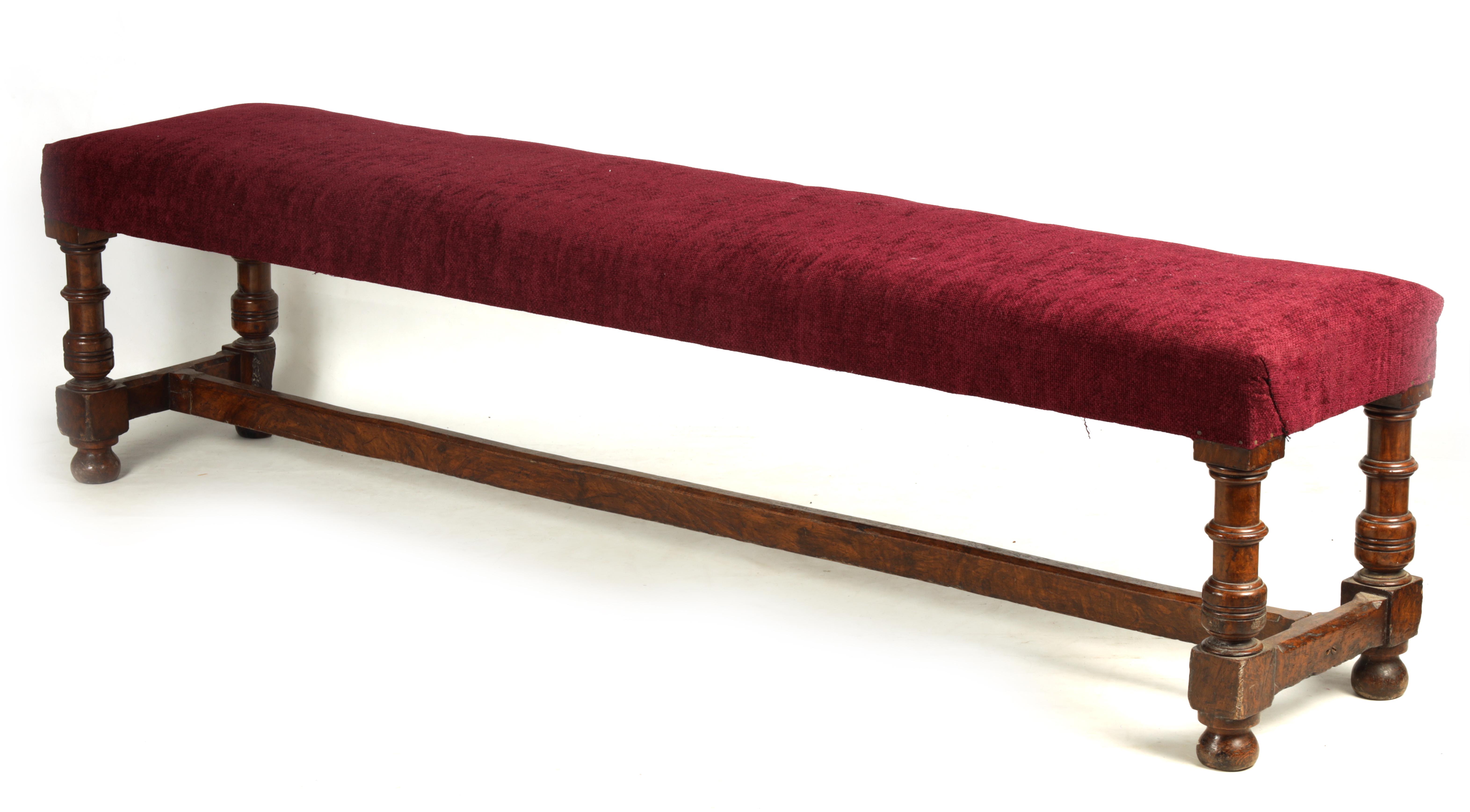 A 19TH CENTURY WALNUT WINDOW SEAT with upholstered top; standing on ring turned legs joined by a H