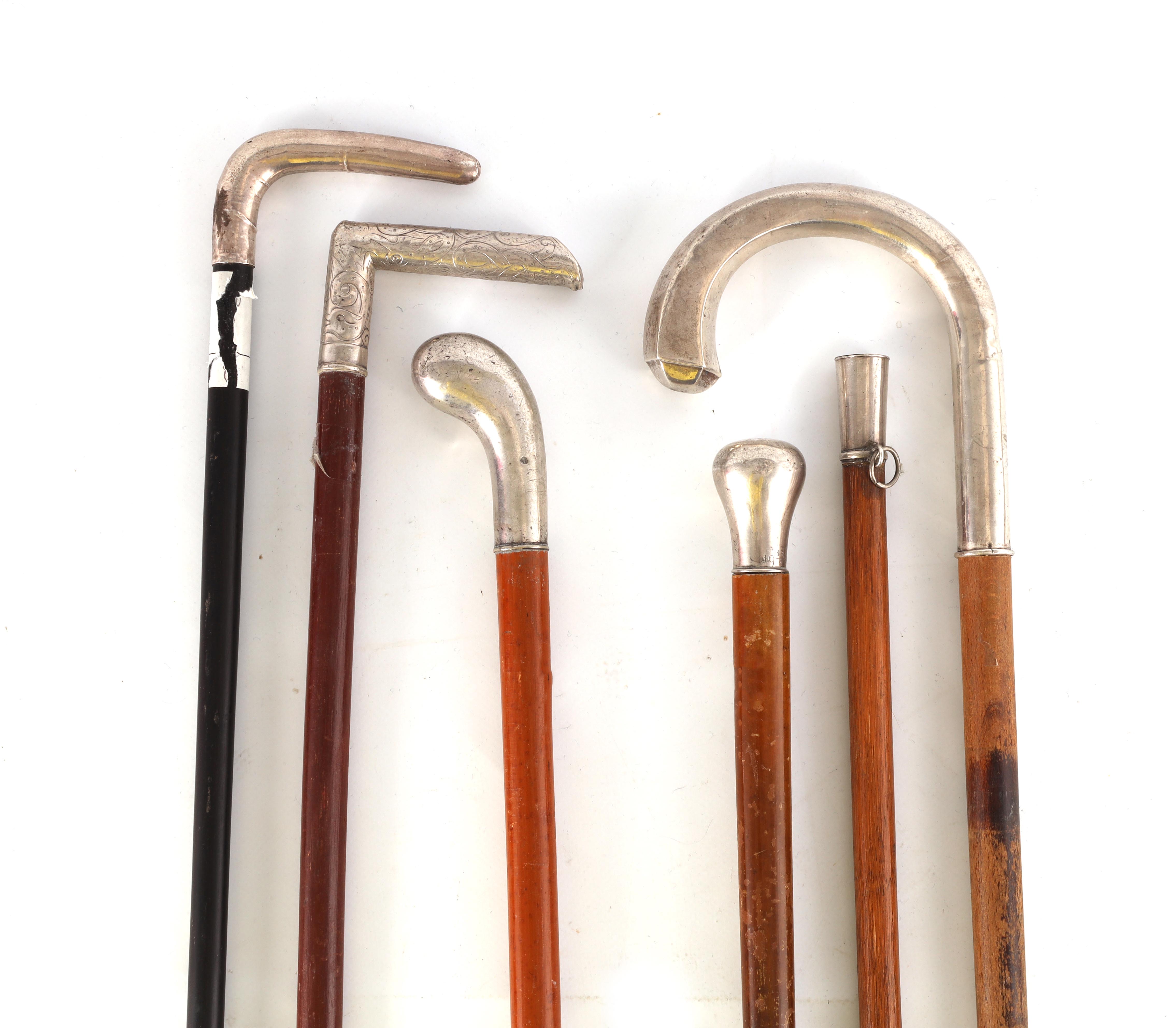 A COLLECTION OF FIVE SILVER TOPPED WALKING STICKS AND A SWAGGER STICK of various designs with