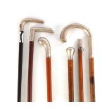 A COLLECTION OF FIVE SILVER TOPPED WALKING STICKS AND A SWAGGER STICK of various designs with
