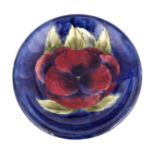 A WILLIAM MOORCROFT BURSLEM SHALLOW DISH decorated in the Big Pansy pattern on a dark blue mottled