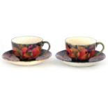 A PAIR OF EARLY MOORCROFT BURSLEM CABINET CUPS AND SAUCERS decorated in the Pomegranate pattern on a