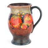 A 1930S MOORCROFT OVOID JUG WITH RIBBED FOOT decorated in the Leaf and Berry patten on a