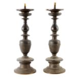 A PAIR OF EARLY 17TH CENTURY BRONZE PRICKET CANDLESTICKS having circular drip trays on baluster ring