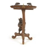 A LATE 19TH CENTURY SWISS CARVED BLACK FOREST SMOKERS TABLE with leaf carved top having two bear