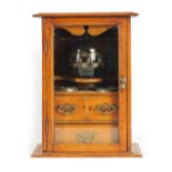 A STYLISH EDWARDIAN OAK SMOKERS CABINET with glazed door enclosing a shelved three drawer interior