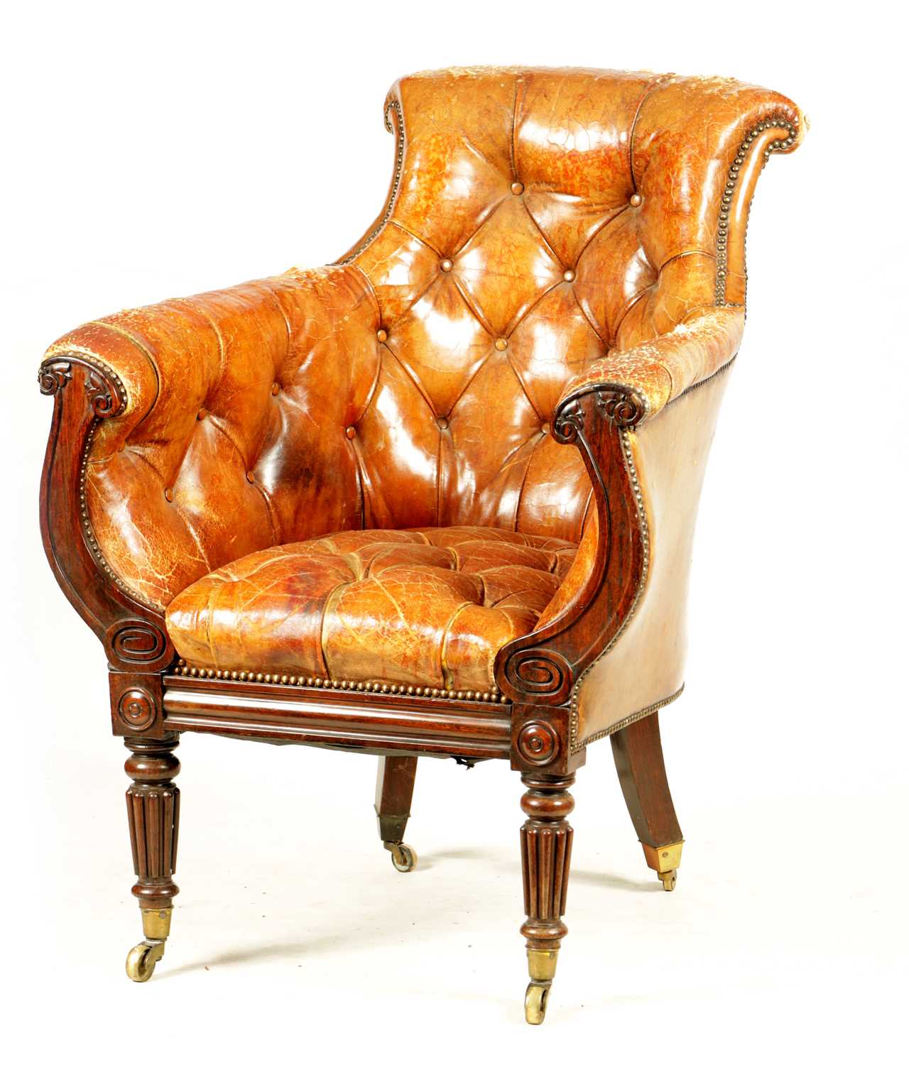 A LATE REGENCY ROSEWOOD FRAMED AND STUDDED TAN LEATHER UPHOLSTERED LIBRARY CHAIR