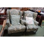 Pair of Edwardian Wing armchairs with green foliate upholstery supported on ball and claw feet