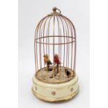 A 20th century Swiss musical bird cage, containing two feather clad birds, on the base decorated