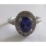An oval tanzanite and diamond cluster ring with diamond shoulders on 18ct white gold band