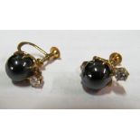 A pair of 14k black pearl and single diamond earrings
