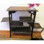 A 1920s oak multi tier occasional table with two drop down side shelves and carved edges