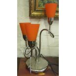 A chrome finish table lamp with orange shades