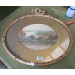 An oval watercolour river scene in gilt frame with bow crest
