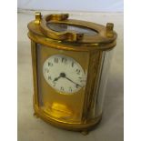 An oval brass carriage clock, the circular dial missing glass panel (not working)
