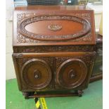 An oak bureau with a fitted interior, two cupboards opening to reveal three drawers 32.5”w