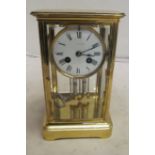 An early 20th Century lacquered brass four sided glass clock with mercurial pendulum and chiming