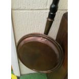 A brass warming pan with turned wood handle