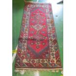 A Persian style rug red ground with stylized floral borders
