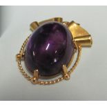 A gold coloured and purple stone pendant