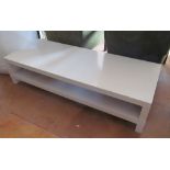 A modern long white coffee table with shelf under