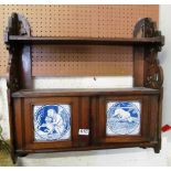 An Edwardian two tier wall shelf with tile inset cupboard of monkey with cat and a dog looking in