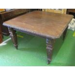 An Edwardian carved oak extending table on square tapered legs