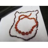 A garnet bead necklace and another amber coloured bead necklace